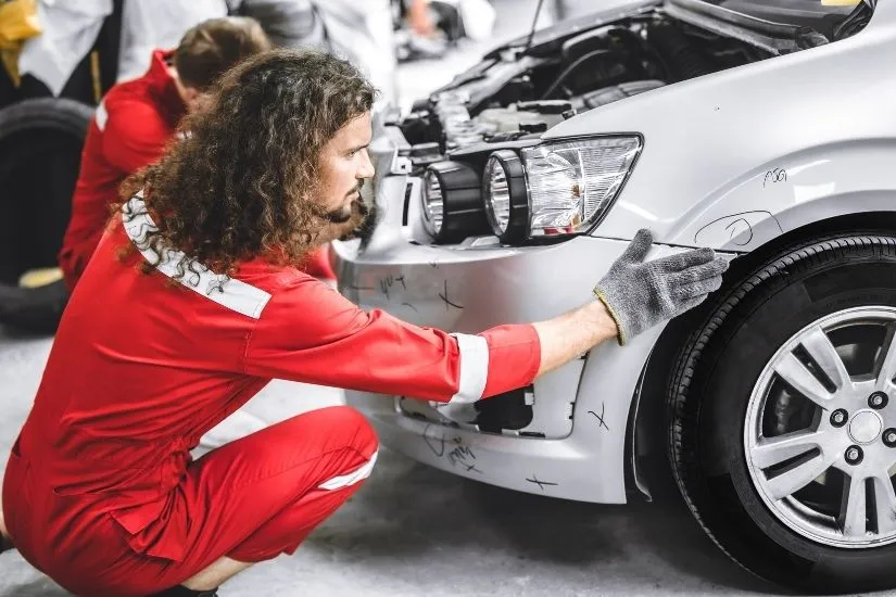 Man repairing damaged car at auto body shop
